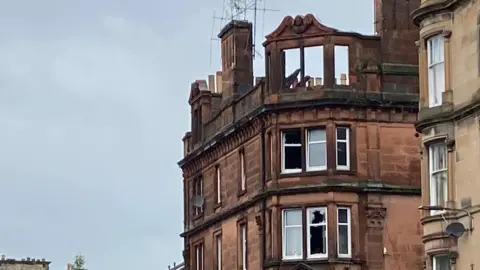 A tenement block in Perth which has been badly damaged by fire. the roof and upper windows have collapsed and several other windows are smashed.