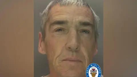 A man with short grey hair is staring at the camera.