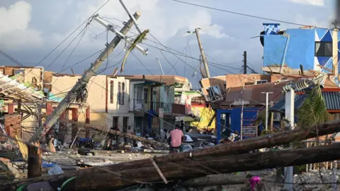 Wreckage and collapsed buildings, with a telegraph pole leaning across a street, in the aftermath of Hurricane Melissa