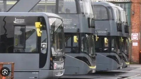 Four grey and yellow Blackpool Transport buses with three double deckers and one single decker in the bus depot.