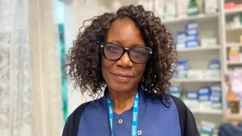 A woman with dark brown curly hair stood in a pharmacy