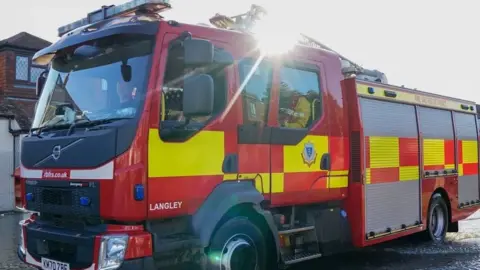 A stock photo of a fire engine driving down a residential street