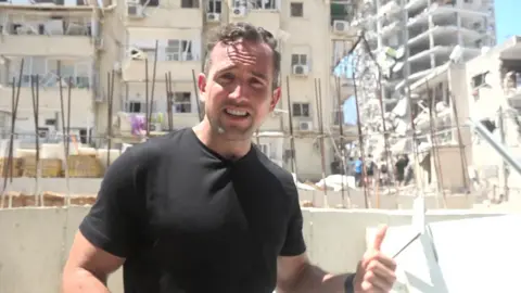 Hugo Bachega in front of a damaged building in Israel's Bat Yam