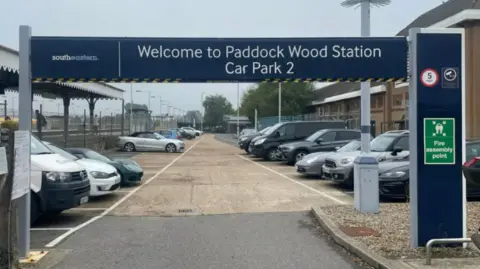 The entrance to a station car park at Paddock Wood station. A sign on the height barrier says: "Welcome to Paddock Wood Station Car Park 2"