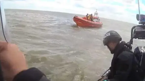 Essex Police Police officers in the water with a little boat.