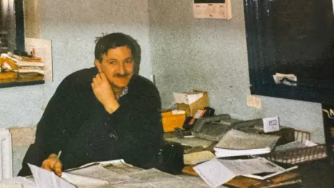 And old photo sees John, Charlie's grandfather, in his middle ages, sat at a desk surrounded by piles of paperwork and books. 