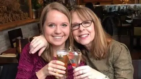 Julie Devey Poppy and her mother Julie looking into the camera holding a drink and smiling