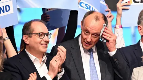 Friedrich Merz wipes as he is joined by party colleagues in a Munich beer hall for a final rally