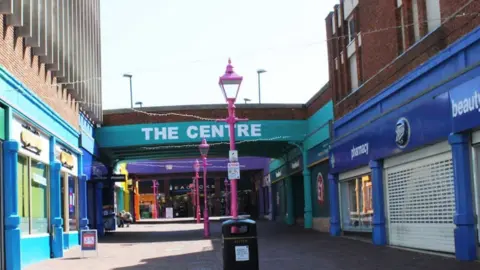 Google The Centre in Margate, with brightly coloured buildings and pink lampposts viewed on a sunny day.