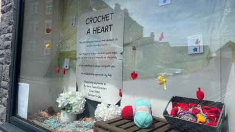Window display of crocheted hearts in PJ Harris Funeral Directors