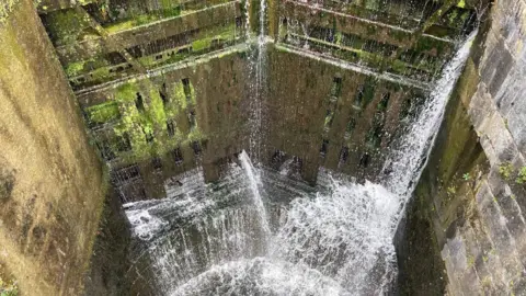 Water pouring out of a pair of lock gates and cascading down into a canal bottom pound.