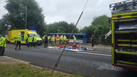 Emergency services at the scene and the bus in the background