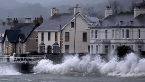 Waves break against the sea wall in Carnlough on the north east coast of Northern Ireland early in the morning of January 24, 2025.