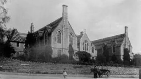 Stroud Hospitals League of Friends A large hospital building in a black and white photo. There is a person beside a cart.