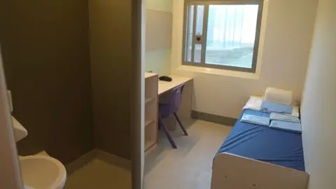 Danny Lawson / PA Media One of the cells at HMP Millsike it has a large window, a single bed, desk and chair and toilet 