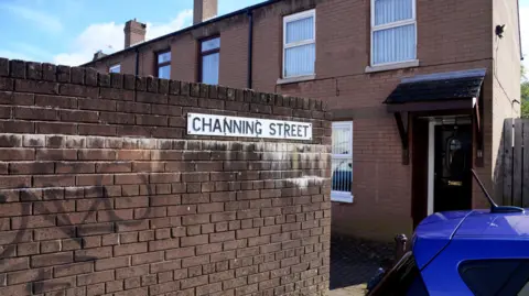 A road sign on a red brick wall. The sign says Channing Street.