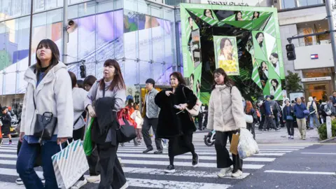 Pedestrians carry shopping bags in the Harajuku district of Tokyo, Japan.