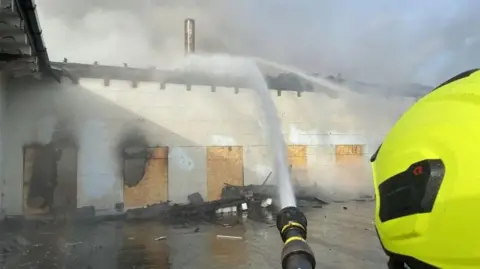 Firehoses being used to dampen down the boarded up stable block at the mansion.