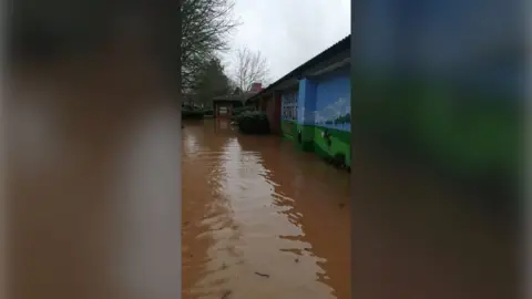 Taunton Bowling Club Huge pool of water outside a building. It looks murky and is next to a big bricked wall which says Taunton Bowling Club on the side.