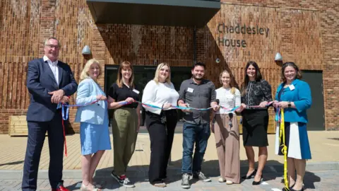 Dorset HealthCare University NHS Foundation Trust A group of people cutting a ribbon outside a brand new inpatient unit at a hospital called Chaddesley House
