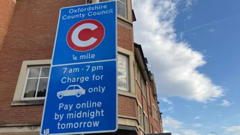 LDRS A roadside congestion charge sign, which reads "Oxfordshire County Council. 7am - 7pm charge for cars only. Pay online by midnight tomorrow."