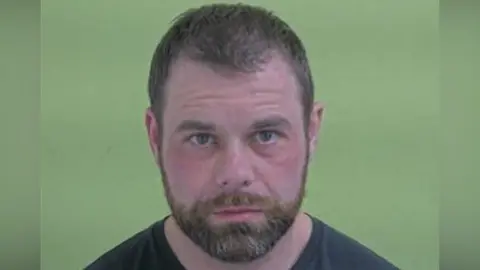 Mugshot of Binding, who has short brown hair and a beard.