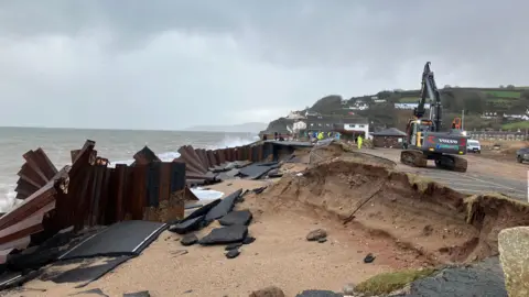 The A379 Slapton Line between Torcross and Slapton has washed away. The image shows a gaping hole in the street.
