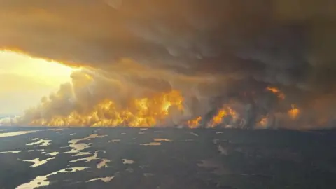 A handout photo made available by the government of Manitoba shows a large wildfire near Flin Flon, Manitoba, Canada. It shows woods and flames with large plumes of smoke filling the sky