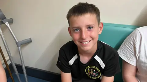 Ollie Conopo/BBC Boy with short brown hair in a black T-shirt smiling