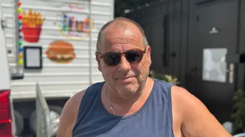 George King/BBC A head and shoulders image of Neil Austin. He is wearing dark sunglasses and a navy blue vest. He is looking directly into the camera.
