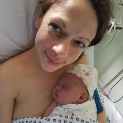 Charlotte Dron Charlotte lies in a hospital bed with her baby son on her chest.