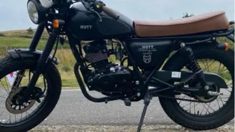 South Yorkshire Police A motorbike with a brown seat, pictured against the backdrop of a country lane and fields.