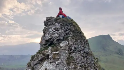A person on on top of a very steep rocky hill