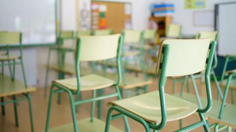 An empty classroom with green chairs 
