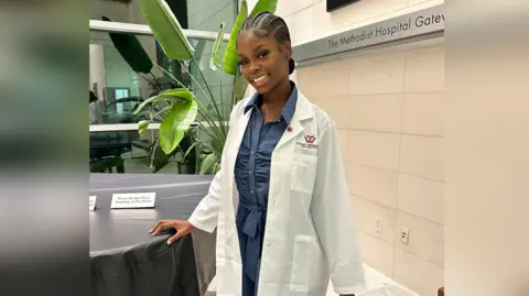 Tami Odunsi Tami Odunsi in a medical coat leans on a piano