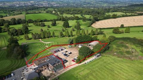 An aerial view of the site that could be developed with green fields in the background