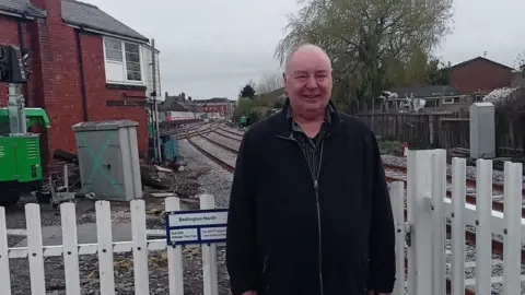 Dennis Fancett is standing by Bedlington Station. He's an older, balding man wearing a black fleece