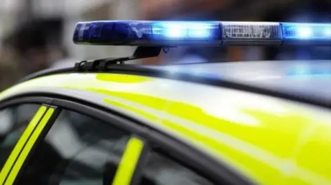 The top of a bright yellow police car with the blue lights on the car roof.