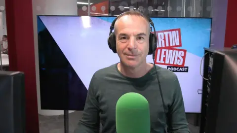 Martin has headphones on his head and is wearing a green long-sleeved top 
