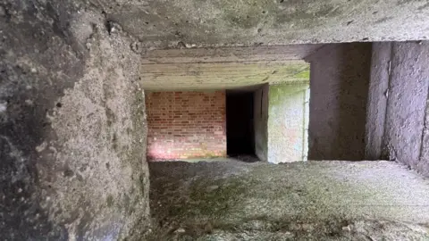 A picture of the inside of one of the pill boxes, which shows brick walls at the back of the structure.