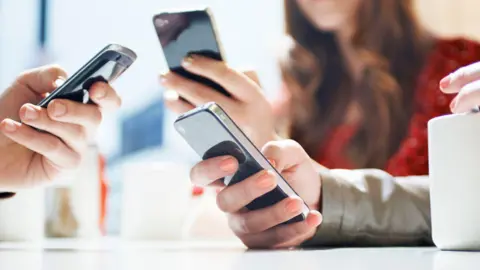 Getty Images A group of three people look at their phones