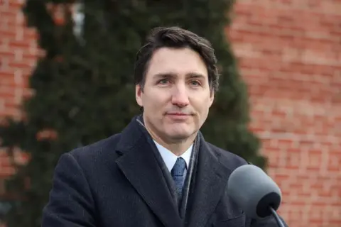 Reuters Canadian Prime Minister Justin Trudeau seen stood behind an outdoor podium while announcing his resignation