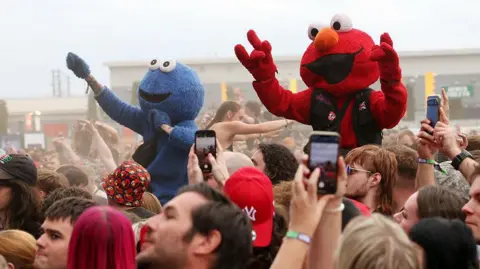Getty Images Two life-sized costumes of the Sesame Street characters the Cookie Monster and Elmo stood on people's shoulders at the Reading Festival.