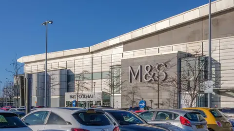 Getty Images A shopping centre with a sign for M&S with a number of parked cars in the foreground