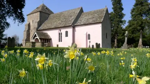 Robin Bennion A small Norman church with daffodil heads in the foreground.