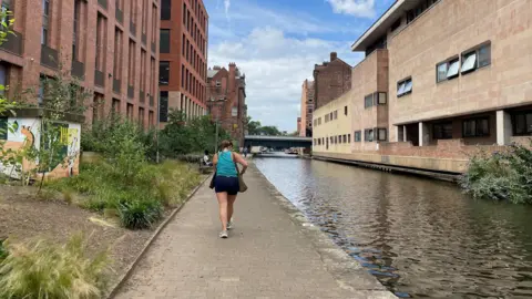 Lady in blue top walking down a canal path