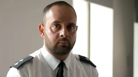 Inspector Moloy Campbell - he is pictured at shoulder height and is wearing a white police shirt - with epaulets showing his rank - and a black tie 