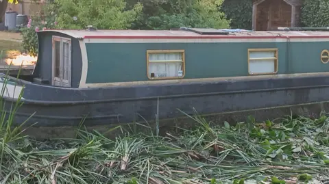 Gerri Martin A boat on a canal which is surrounded by leaves 