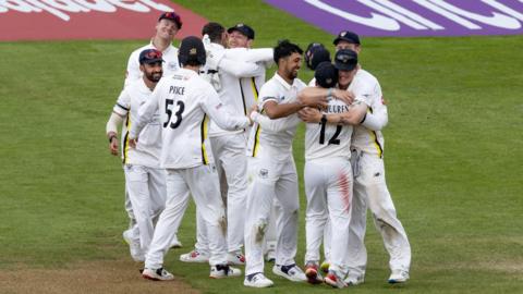 Gloucestershire players hug each other in celebration 