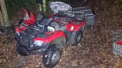 The stolen red quad bike, looking a bit worse for wear, in a wooded area in the dark